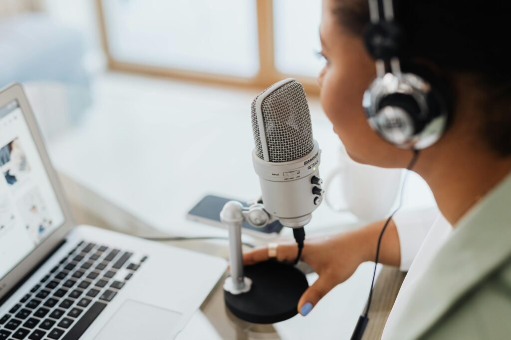 Professional woman recording a podcast or broadcast using a microphone and laptop at a desk.